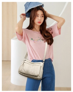Close-up of cream soft leather handbag featuring functional triple front zipper pockets