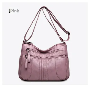 Detail of pink soft PU leather crossbody bag featuring multiple functional zip pockets