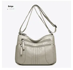 Detailed front view of beige soft leather crossbody bag with multiple zip pockets