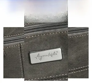 Close-up of sleek silver logo plate and high-quality gray canvas texture on crossbody bag