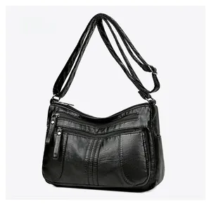 Side view of black faux leather crossbody bag with multiple zippers and pebble texture