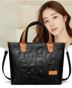 Detail of embossed lettering and brown leather handles on a black tote handbag