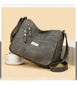 Detail of multi-pocket dark olive crossbody bag with metallic logo on textured fabric