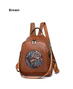 Detail of brown vintage leather backpack showing elephant embroidery and dual zipper