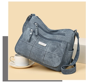 Close-up of blue multi-pocket canvas crossbody bag with quilted flap and metal logo