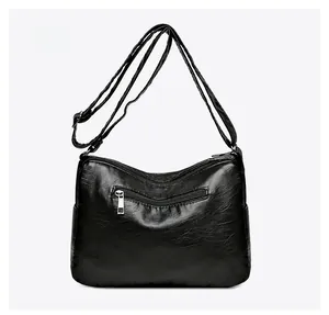 Detail of black crossbody bag back with zipper pocket and adjustable leather strap