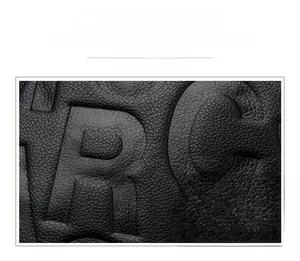 Detail of black lychee grain leather tote with embossed letters and red contrast tag