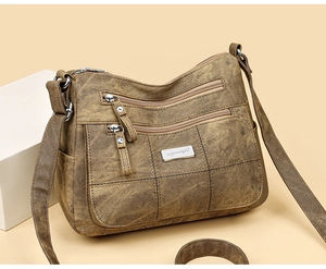 Detail view of brown textured leather crossbody bag with multiple zipper compartments