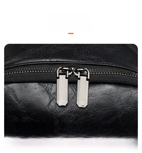 Close-up of dual silver metal zippers on black lychee-patterned leather backpack