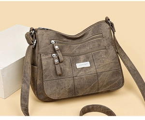 Detail of dark brown vintage faux leather crossbody bag with multiple zippers and stitching