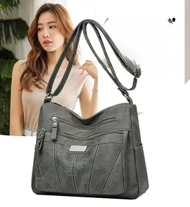 Detail of grey crossbody bag featuring multiple zipper pockets and textured matte finish