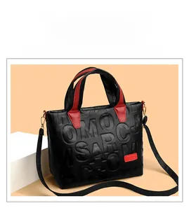 Detail of black embossed tote bag with red handles and adjustable shoulder strap
