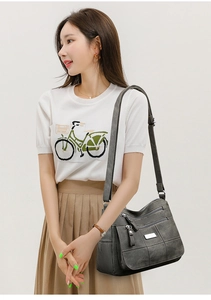Detail of dark grey multi-pocket crossbody bag showing zippers and matte texture
