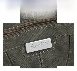 Detail showing the silver metal logo and intricate cross-pattern stitching on dark gray bag