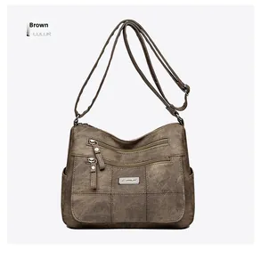 Detail of vintage brown PU leather crossbody bag with dual zippers and silver logo