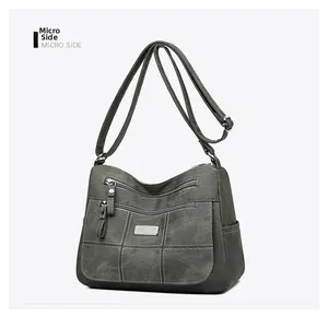 Close-up of multi-zippered crossbody bag with white stitching and dark gray matte fabric
