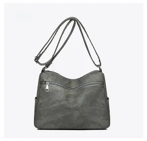 Detail view of the back of a charcoal gray crossbody bag with zipper pocket and side slots
