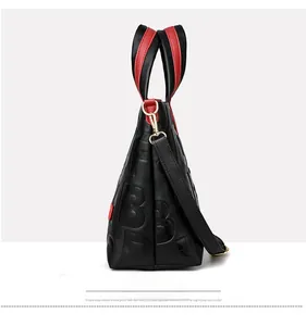Detail of black pebbled leather tote with B-letter embossing and red contrast handle