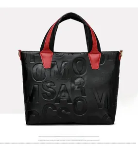 Detail of lychee textured leather tote bag with letter embossing and golden D-rings