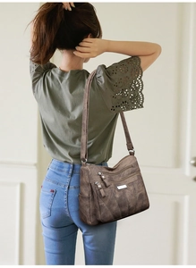 Detail of dark brown faux leather crossbody bag with multiple tiered zipper pockets