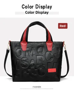 Detail of black embossed tote bag with vibrant red leather handles and shoulder straps