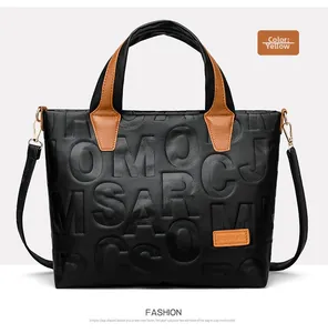 Detail of embossed letter texture on leather tote bag with brown straps and gold hardware