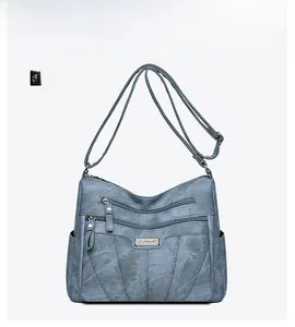 Close-up of blue embroidered crossbody bag with double zipper pockets and metal logo