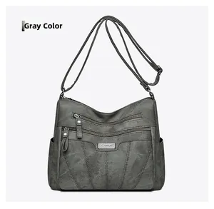 Close-up of grey textured crossbody bag featuring three front zipper pockets and side pockets