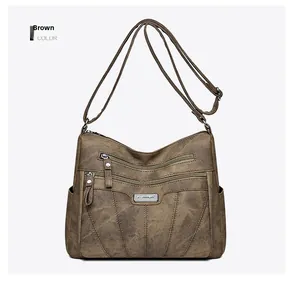Detail view of brown faux leather crossbody bag with multiple zippers and stitching