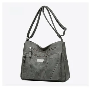 Side view of dark gray crossbody bag with multiple zippers and curved embroidery detail