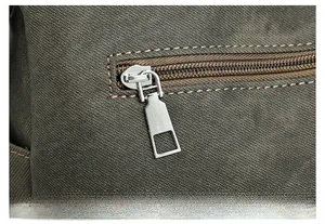 Detailed close-up of smooth silver zipper and durable canvas fabric on the handbag