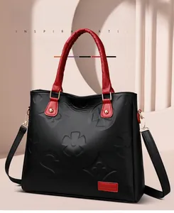 Detail of embossed clover pattern on black faux leather handbag with red accents