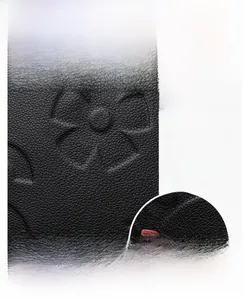 Close-up of black embossed floral leather handbag with red logo brand tag detail