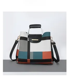 Detail of color-block geometric pattern handbag with silver handle and gold logo plate