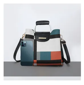 Crossbody bag size comparison with a smartphone showing multi-color geometric panels