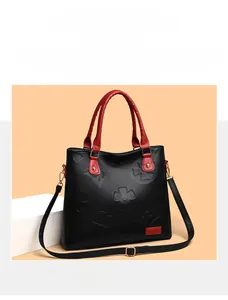 Close-up of black and red embossed leather tote bag with elegant floral pattern details
