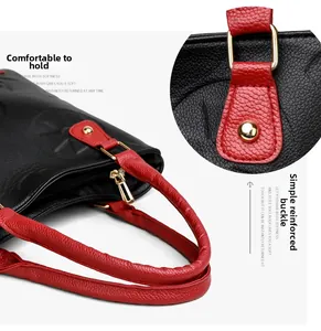 Detail of red and black lychee leather handbag with reinforced gold metal hardware buckles
