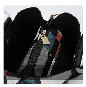 Detail view of smooth metal zipper and plaid fabric lining inside the black crossbody bag