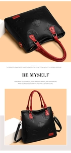 Detail of embossed floral texture on black and red faux leather handbag with gold hardware