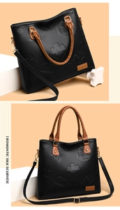 Detail of embossed clover pattern on black lychee leather with brown handles and strap