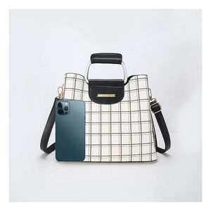 Striped plaid crossbody bag shown next to a smartphone for clear size comparison