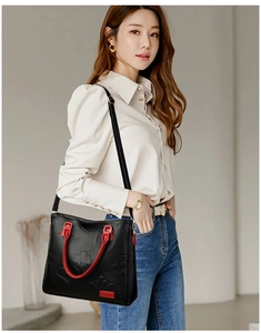 Close-up of floral embossed leather handbag with red trim and metallic brand plaque