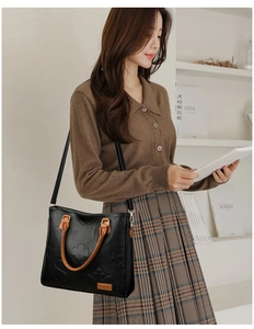 Detail of embossed floral pattern and S-monogram on black PU leather handbag for women
