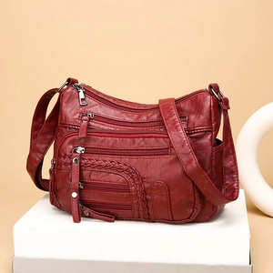 Burgundy woven leather crossbody bag with multiple zippers and wide shoulder strap