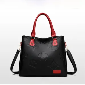 Close-up of embossed floral pattern on black lychee grain faux leather with red trim