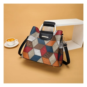 Detail of colorful geometric patchwork leather crossbody bag with metal ring handles