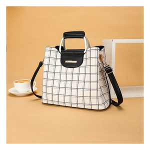 Detail of grid pattern crossbody bag with golden hardware and leather handle