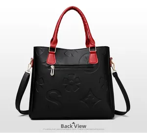 Detailed back view of large tote bag with floral embossing and red woven handles