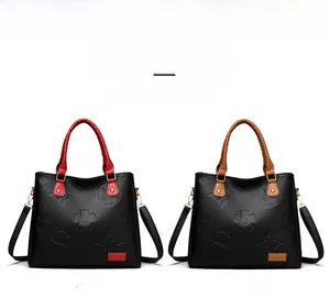 Detail showing two textured leather handbags in red and brown with embossed floral patterns