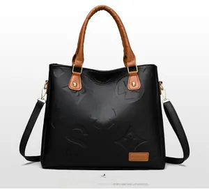 Detail of floral embossed leather handbag with brown handles and gold hardware